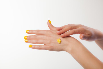 Female hands on a white background. Cream, yellow moose on the skin.