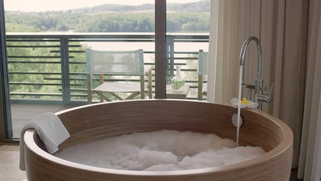 
Wooden bath tub with running water and a bubble bath
