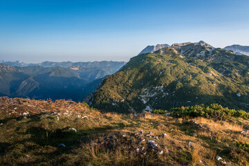 Alps mountains in early morning in summer season. Summit covered with grass and rocks. Beautiful elevated view of mountains in the distance. Hiking in Slovenia, wide shot