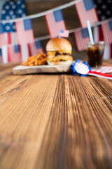 Fourth of July celebration. American flag and decorations. Burgers on rustic wooden table.