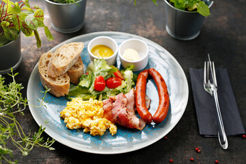 Continental breakfast, scrambled eggs, fried sausage, bacon and vegetable salad. Ready dish served in a hot pan. Suggestion of serving a dish on a plate. food background
