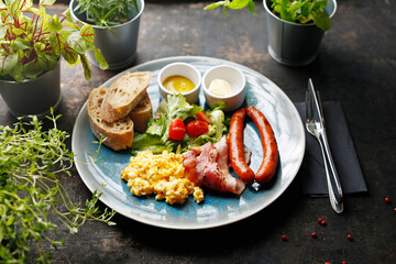 Continental breakfast, scrambled eggs, fried sausage, bacon and vegetable salad. Ready dish served in a hot pan. Suggestion of serving a dish on a plate. food background