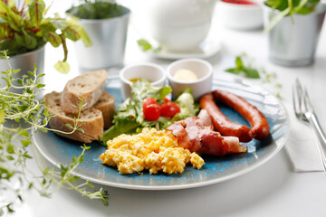 Breakfast, scrambled eggs, fried sausage and vegetable salad. Ready dish served in a hot pan. Suggestion of serving a dish on a plate. food background