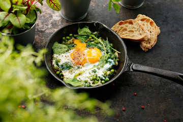 Eggs baked with green peas and spinach. Ready dish served in a hot pan. Suggestion of serving the dish. food background