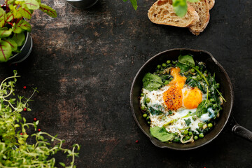 Shakshouka, eggs baked with green peas and spinach. Ready dish served in a hot pan. Suggestion of serving the dish. food background