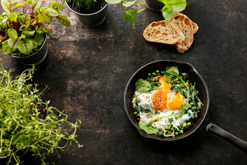 Baked eggs with green peas and spinach. nutritious healthy breakfast. Ready dish served in a hot pan. Suggestion of serving the dish. food background