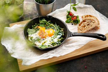Eggs baked with green peas and spinach. Ready dish served in a hot pan. Suggestion of serving the dish. food background