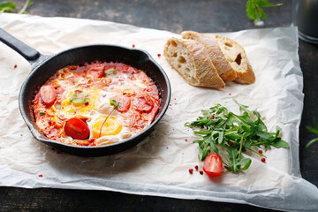 Eggs and tomatoes baked in a pan. Ready dish served in a hot pan. Suggestion of serving the dish.