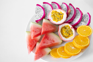 White plate of sliced fruit. Fresh fruits and vitamins. Still life colored summer fruits.