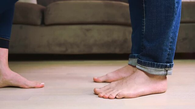 Man and woman feet wearing blue jeans dancing at home, close up