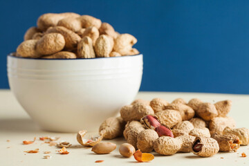 A handful of peanuts in shells and in a bowl. The concept of a healthy diet, a snack for vegetarians, vegetable fats.