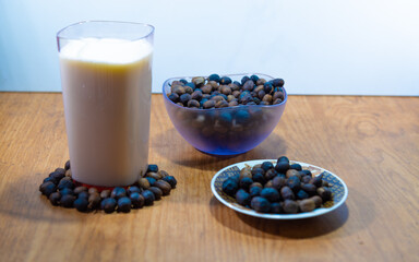 Glass with milk along with roasted coffee beans.