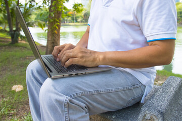 A man is typing on a laptop keyboard works in the park concept Workspace anyware and Remote online work