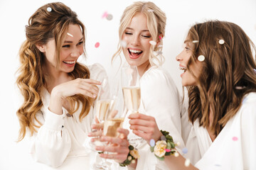 Photo of excited beautiful bridesmaids laughing and drinking champagne