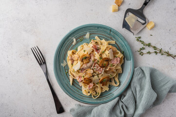 Top view pasta fettuccine with mushrooms, bacon, parmesan cheese in white plate with fork and...