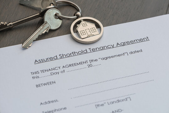 Real estate rental tenancy agreement on a table with keys and house keyring. New home concept.