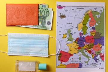 the map of europe, euro paper banknotes in cash and means of individual safety protection as the concept of traveling or tourism abroad during pandemic period or flu season 
