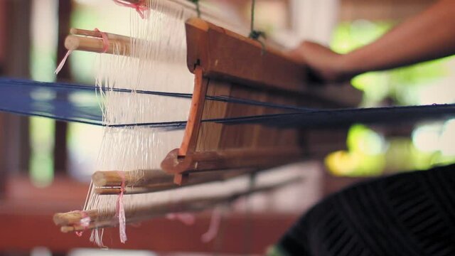 Vientiane, Laos. Close up back view of woman&acute;s hands while she hand weaves silk on a handcrafted loom.