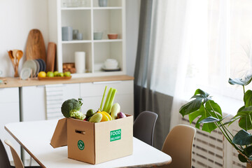 Image of fresh vegetables in cardboard box on the table in domestic kitchen