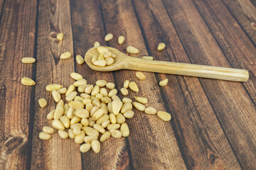Many pine nuts with wooden spoon and wooden background