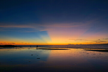 Fototapeta na wymiar Kuta beach sunset lans sun rays in blue sky, Bali island, Indonesia