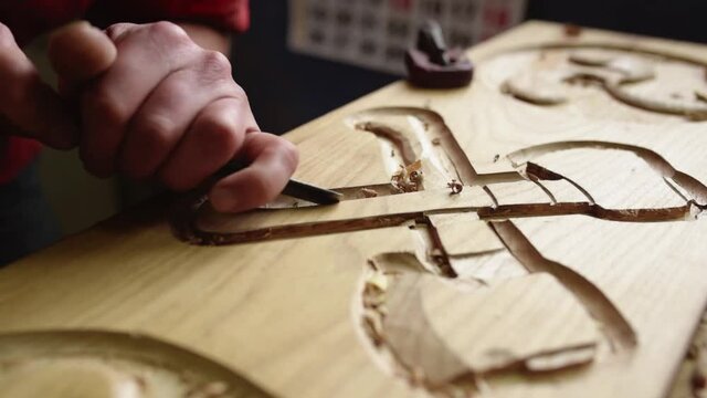 Craftsman carving elements on wood in workshop