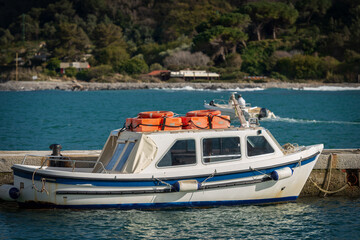 Small white and blue motor boat with orange lifebelts on the top, moored in the port of Portovenere or Porto Venere. La Spezia, Liguria, Italy, Europe