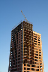 Fototapeta na wymiar construction of a high-rise building against the blue sky, multi-storey building, red brick house
