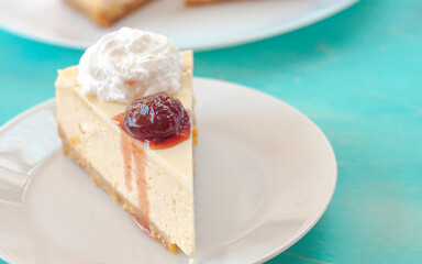 portion of cheesecake with jam on a white plate with cream