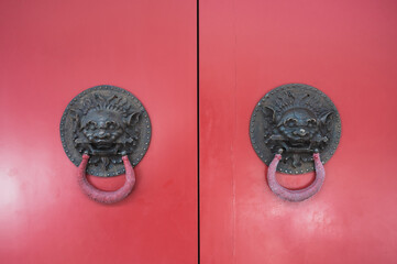 Red chinese temple door with black metal lion knocker
