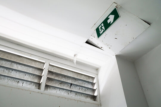 Open ceiling panels in roof office building with emergency exit sign selective focus on ceiling open.