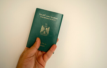 Egyptian passport in male hand. Man hand is holding Egypt international passport on light white background with copy space.