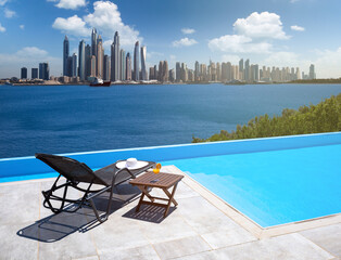 Infinity pool with chairs and table With a view of the Dubai Skyline