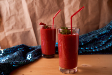Strawberry and banana smoothies with long glass glasses on wooden table. Blue blurred background