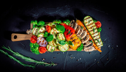 Grilled vegetables and mushrooms with basil and dry herbs on a dark background. Vegan grill concept