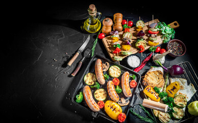 Grilled sausage and mixed vegetables with basil and dry herbs on a dark background