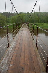 Obraz premium suspension bridge over the river on a rainy day.