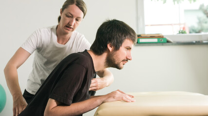 Physiotherapist exercising with disabled person on a therapy table.