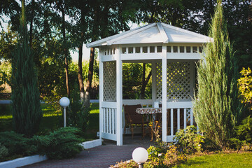 White wooden arbor on the street in a green park. A cozy place to spend time