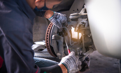 A car mechanic working grinding brake disc with grinding machine and vehicle brake disc turning for...
