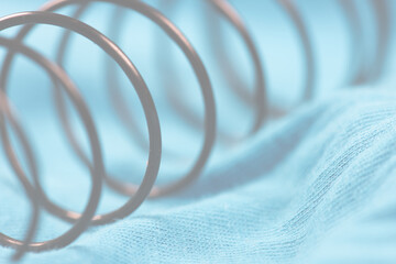 Details of a metal spring on blue cloth.