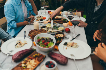 Cropped image of best friends dining together by candles at home terrace eating local mediterranean food and drinking homemade wine, Dinner Party Concept, family celebrating having fun together
