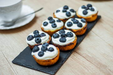 cupcakes with cream, blueberries and mint on a grey background