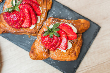 Delicious puff pastries with berries and sugar powder on wooden background