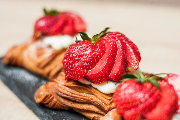 Delicious puff pastries with berries and sugar powder on wooden background
