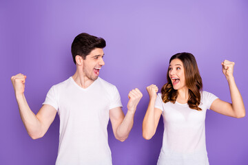 Portrait of ecstatic lucky spouses win honeymoon lottery raise fists scream yeah wear good look clothes isolated over purple color background