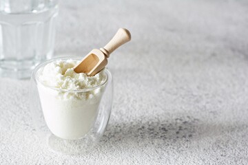 Collagen powder with a glass of water on a light background. Extra protein intake. Natural beauty and health supplement for skin, bones, joints and gut. 