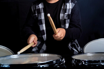 The boy holds drumsticks in his hands. Without a face.