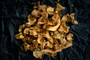 dry chanterelle mushrooms on black crumpled paper. healthy eating concept