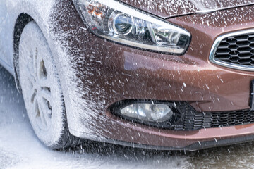 brown car at a car wash. wheels in foam close up